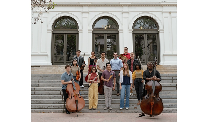 group of young people with their instruments standing on the front steps of the museum entrance